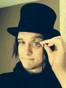 a man wearing a top hat and glasses is holding a chain around his eye