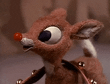 a close up of a stuffed reindeer with a red nose