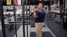 a man in a blue shirt is lifting a barbell in a gym with a yellow flag that says ' army '