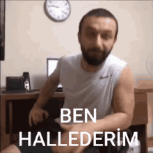 a man with a beard is sitting in a chair in front of a desk with a clock on the wall .