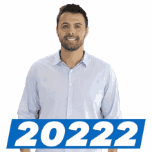 a man in a blue shirt is standing in front of a sign that says 2022