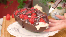 a person is taking a piece of chocolate cake with strawberries and chocolate icing .