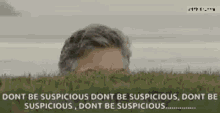 a man is peeking out from behind some grass with a quote .