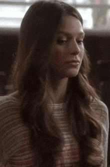 a woman with long brown hair is sitting in a chair and looking at the camera