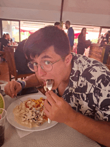 a man with glasses is eating a plate of food