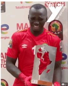 a man in a red shirt is holding a trophy with the number 1 on it