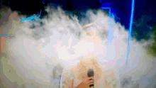 a woman in a white dress singing into a microphone surrounded by smoke