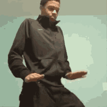 a young man in a black jacket is dancing in a room .