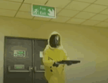 a person in a yellow suit and helmet is holding a gun .