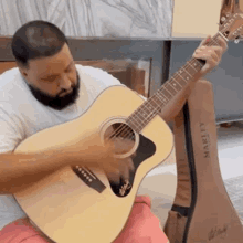 a man is playing an acoustic guitar while sitting on a couch .