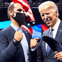 a man wearing a mask stands next to a man wearing a tie