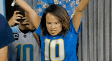 a woman wearing a blue jersey with the number 10 on it is holding her arms up in the air .