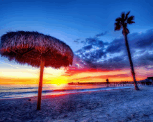 a thatched umbrella sits on the beach near a palm tree