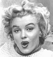 a black and white photo of marilyn monroe making a funny face with her mouth open .