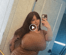 a woman taking a selfie in front of a mirror with a play button in the corner