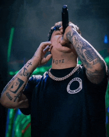 a man with a tattoo on his neck that says boyz singing into a microphone