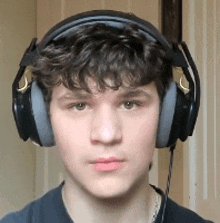 a young man with curly hair is wearing headphones and looking at the camera .