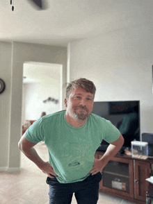 a man with his hands on his hips wearing a green t-shirt that says " friends " on it