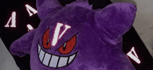 a purple stuffed animal has the letter v on its face