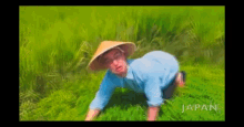 a painting of a man wearing a conical hat in a field with the word japan on the bottom right