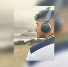 a man wearing a pair of jbl headphones stands on a beach