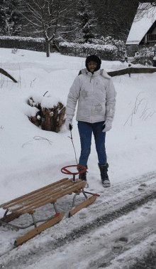 a woman in a white jacket is pulling a wooden sled