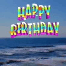 a colorful happy birthday greeting card with the ocean in the background .