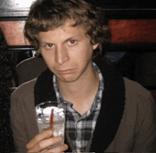 a man holding a glass of water with a straw in it