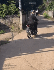 a person riding a motorcycle down a dirt road with a sign above them that says koyorrapan