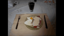 a plate of food with a fork and knife on a table next to a glass of soda