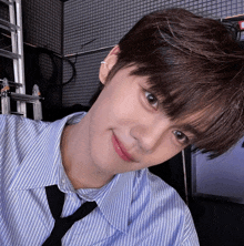 a young man wearing a striped shirt and tie is smiling for the camera