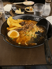 a bowl of ramen with potato chips and a spoon in it