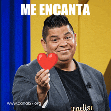 a man in a suit is holding a red heart with the words me encanta written above him