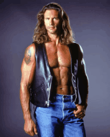 a man with long hair and a tattoo on his arm is wearing a leather vest and jeans