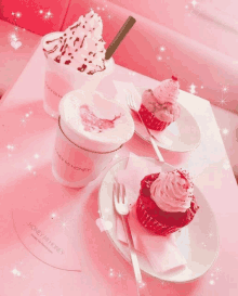 a cup of honey mi honey sits on a pink table next to two cupcakes