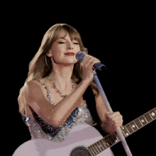 a woman singing into a microphone while holding a pink guitar