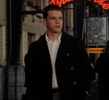 a man in a black jacket and white shirt is walking down a street in front of a sign that says ' coca cola '