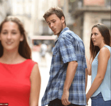 a man in a plaid shirt is walking down the street with two women