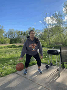 a woman wearing a storm tigers hoodie holds a basketball