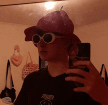 a person wearing a hat and sunglasses is taking a picture of themselves