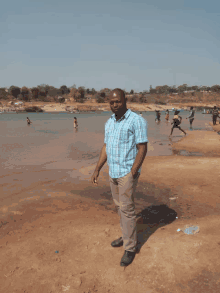 a man in a blue plaid shirt is standing on the beach