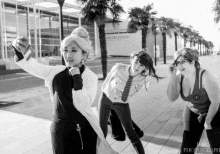 a woman taking a picture of herself with a camera while two other women look on in front of a building that says les congres