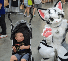 a child in a stroller is crying next to a furry mascot