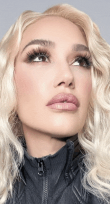 a close up of a woman 's face with blonde hair and a black jacket