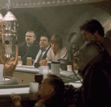 a group of men are sitting at a bar with beer mugs