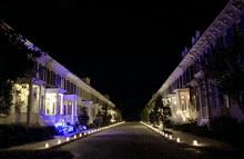 a row of houses lit up at night with candles on the sidewalk