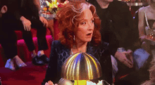 a woman with red hair is sitting at a table with a silver dome on top of it .