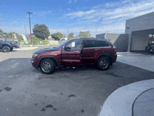 a red jeep grand cherokee is parked in a parking lot