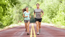 a man and a woman are running down a road together .