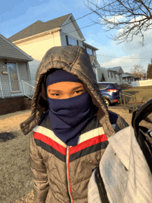 a boy wearing a tommy hilfiger jacket and a blue scarf around his face